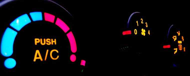 A cars air con control system lit up at night.